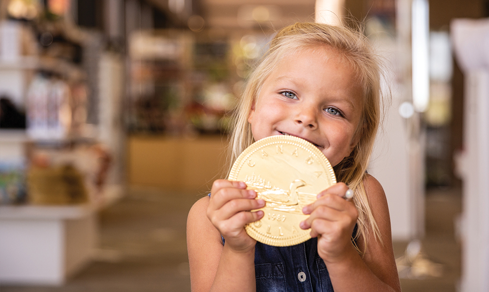 Photo of young girl holding a large gold coin.