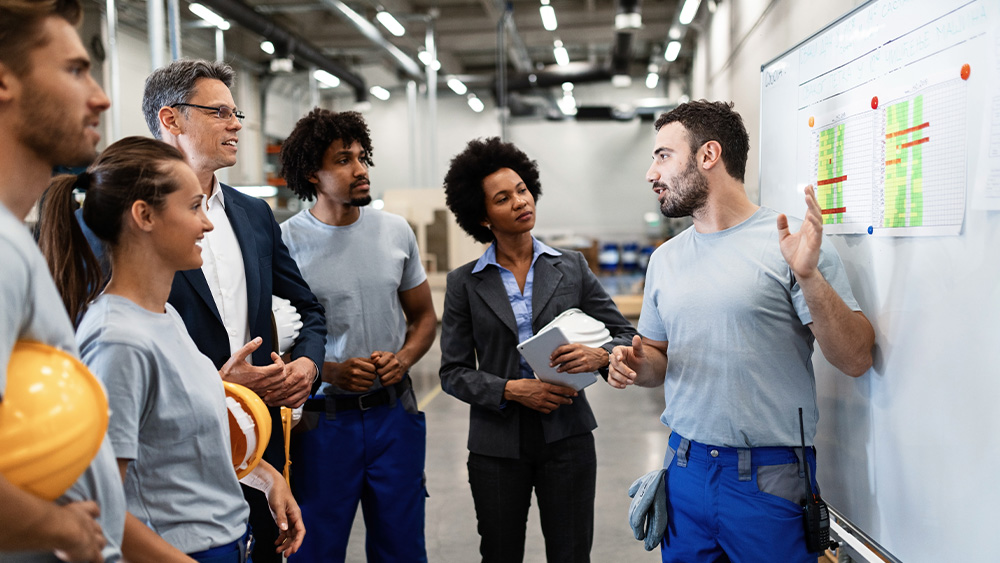 Photo of a group of people reviewing a whiteboard.